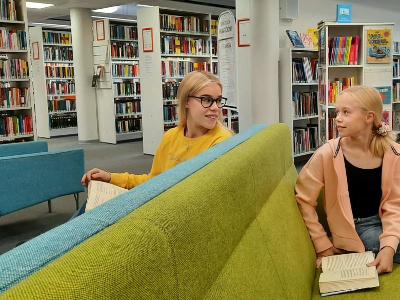 Lukijoita kirjaston nuorten osaston sohvilla