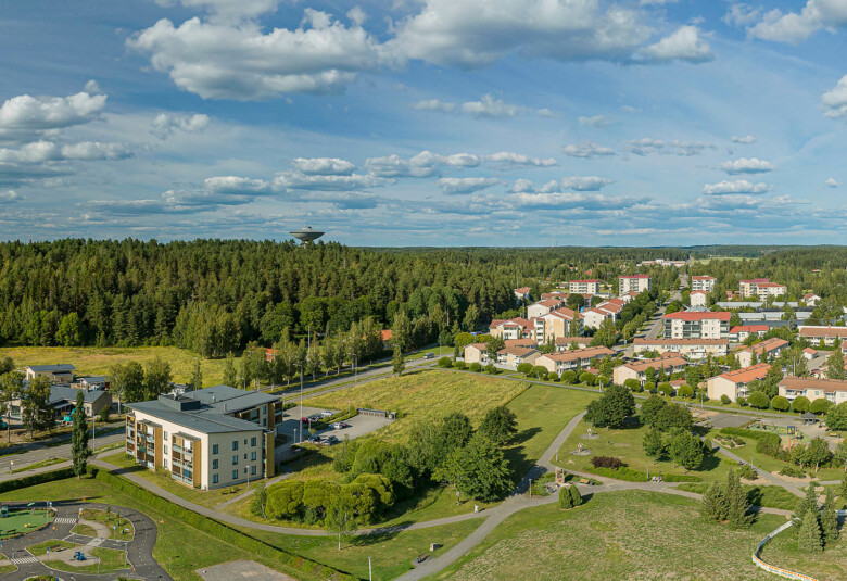 Ilmakuvassa Liedon keskustan asuintaloja ja vesitorni vihreässä kesämaisemassa.