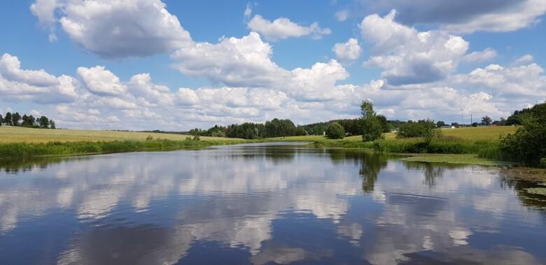 Aurajoki kesäpäivänä. Joen pintaan heijastuvat taivaalta poutapilvet ja sininen taivas.