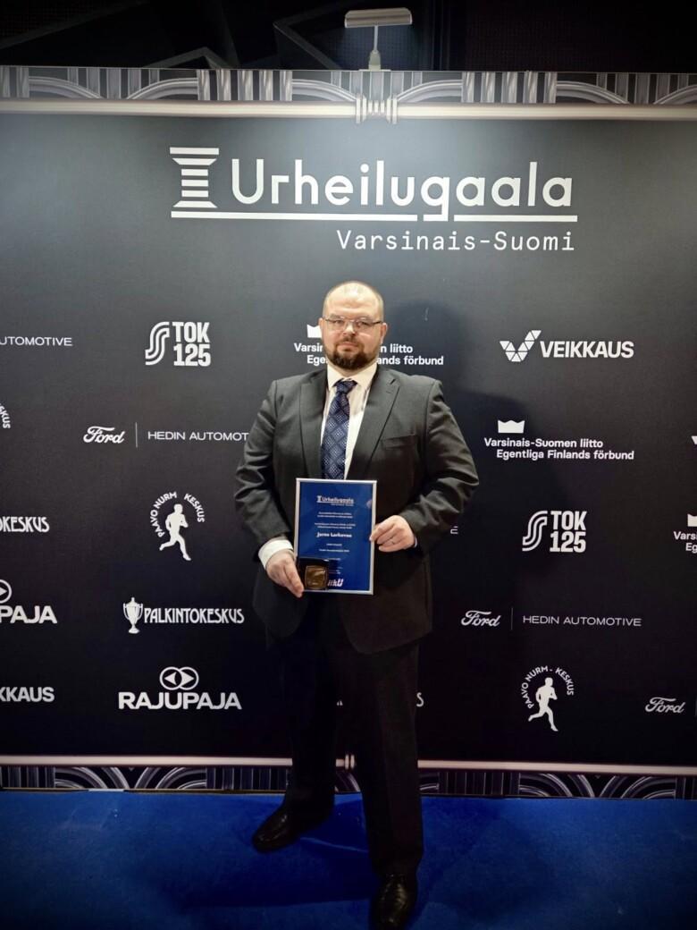 Jarno Larkovuo kunniakirja ja palkinto kädessään.