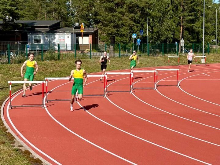 Miehet juoksee yleisurheilukentän juoksuradalla.